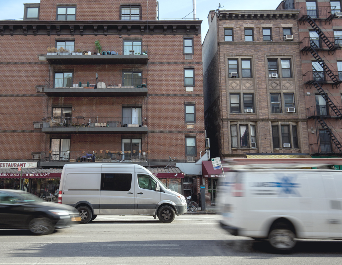 Residential buildings above a busy street with passing vans